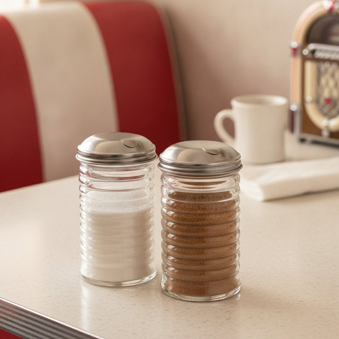 Glass beehive pourers filled with white granulated sugar and cinnamon sugar on a diner counter